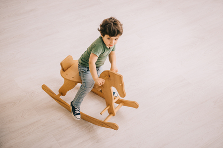 overhead view of little boy in green t-shirt riding on rocking horseの写真素材