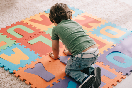 cute child in green t-shirt playing with puzzle matの写真素材