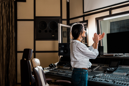 attractive sound producer applauding in recording studio near mixing consoleの写真素材