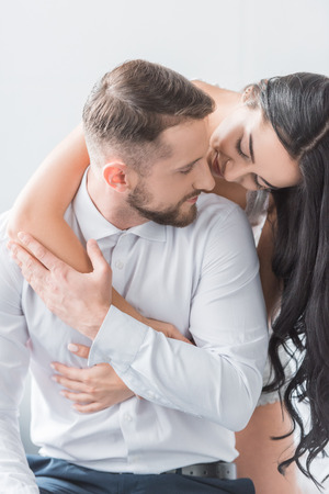 cheerful girlfriend hugging bearded happy boyfriend at homeの写真素材