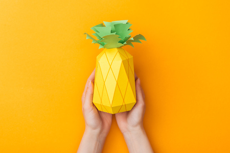 partial view of young woman holding paper pineapple isolated on orangeの写真素材