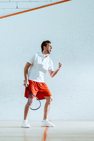 Full length view of happy squash player with racket showing yes gestureの写真素材