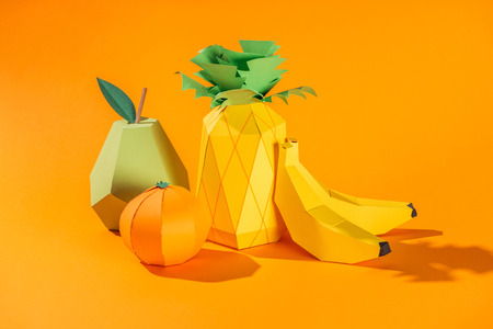 handmade paper pineapple, bananas, pear and tangerine on orangeの写真素材