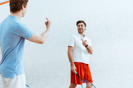 Cropped view of squash players showing middle fingers to each otherの写真素材