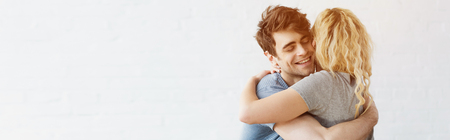 panoramic shot of happy man smiling while hugging blonde girl