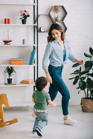 Full length view of smiling woman with son in living roomの写真素材