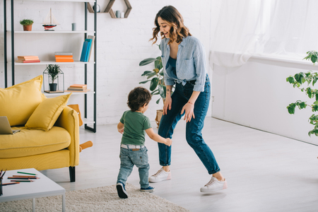 Full length view of smiling woman with son in living roomの写真素材