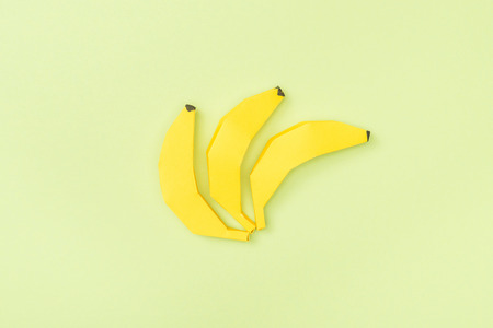 Top view of yellow paper bananas isolated on green backgroundの写真素材