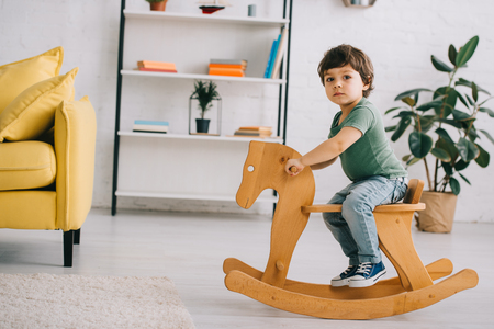 Child sitting on wooden rocking horse in living roomの写真素材