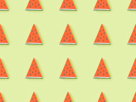 Top view of pattern with handmade red paper watermelon slices isolated on green backgroundの写真素材