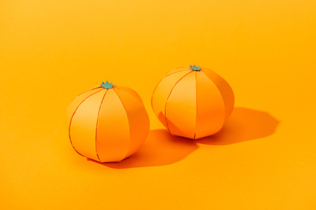 handmade tangerines made of paper on orange with shadowの写真素材