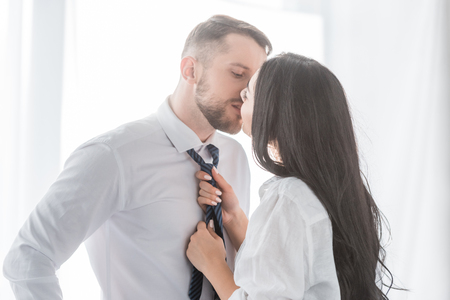 brunette woman kissing handsome boyfriend in formal wearの写真素材