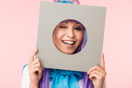 Smiling asian anime girl holding cardboard isolated on pinkの写真素材