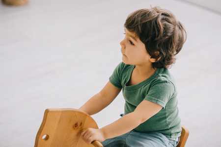 kid sitting on wooden rocking horse in living roomの写真素材