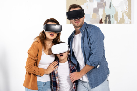 Shocked parents and surprised kid wearing virtual reality headsets at homeの写真素材