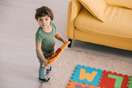 overhead view of cute child in green t-shirt playing with puzzle matの写真素材