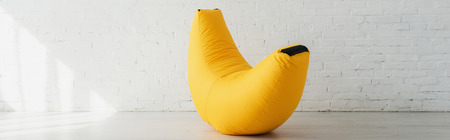 panoramic shot of yellow bean bag chair near brick wall in modern home