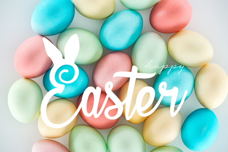 Happy Easter white lettering on background of multicolored painted eggsの写真素材