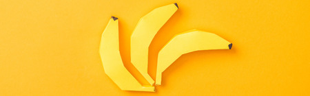 Panoramic shot of yellow paper bananas isolated on orange backgroundの写真素材