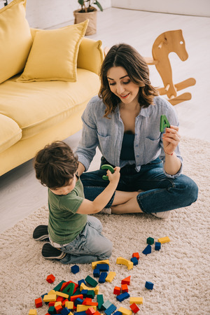 Mother and son playing with toy blocks on carpetの写真素材