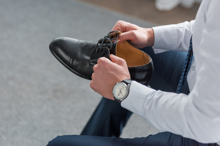 Cropped view of man holding black shoe in handsの写真素材