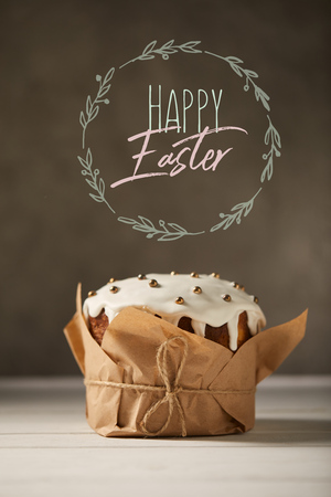 Traditional decorated Easter cake in craft paper with happy Easter lettering in circle on brown backgroundの写真素材