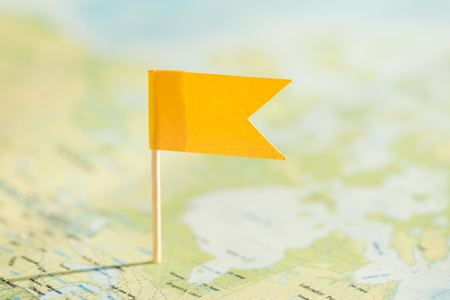 Selective focus of world map and little yellow flagの写真素材