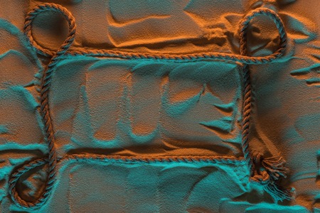 Top view of rope with knots on sand with orange and blue lights and copy spaceの写真素材