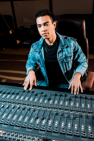 Concentrated mixed race sound producer working at mixing console in recording studioの写真素材