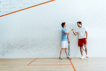 Full length view of squash players shaking hands in four-walled courtの写真素材