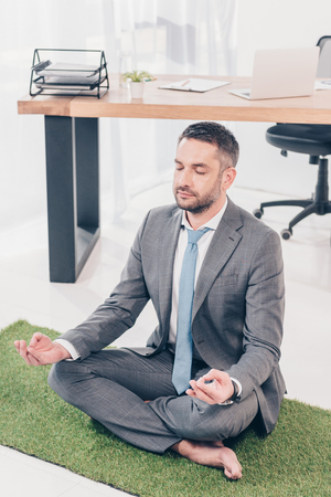 Sitting on grass mat in Lotus Pose and meditating in officeの写真素材