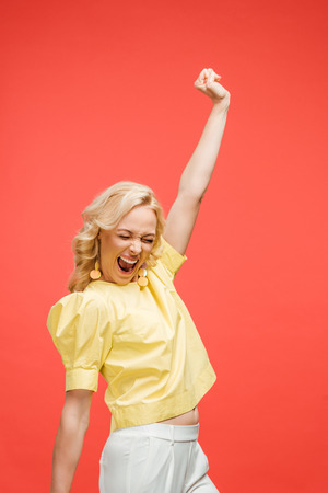 happy blonde woman with closed eyes celebrating success on redの写真素材