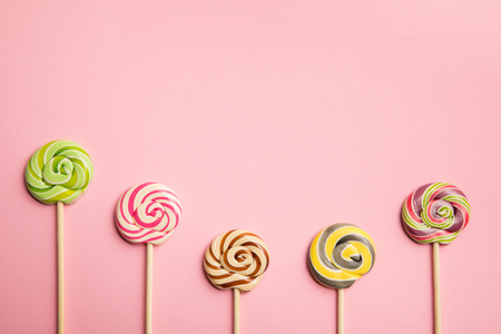Top view of delicious multicolored lollipops on wooden sticks on pink backgroundの写真素材
