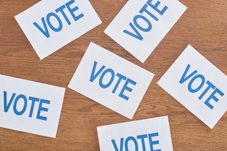 Top view of white cards with blue vote lettering scattered on wooden table backgroundの写真素材