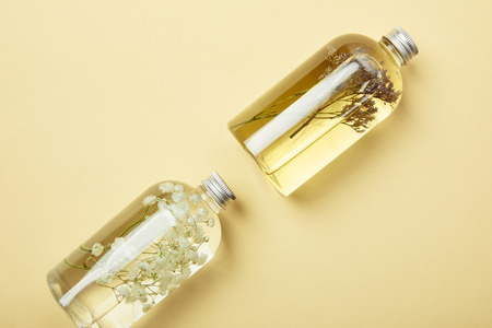 Top view of transparent bottles with natural liquid beauty products and wildflowers on yellow backgroundの写真素材