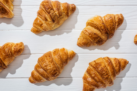 Flat lay of tasty and sweet croissants on white surfaceの写真素材