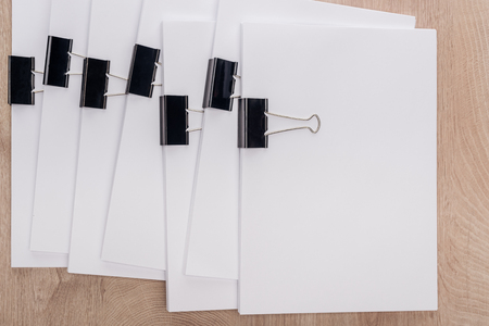 Top view of stacks of blank paper with metal binder clips and copy space on wooden tableの写真素材