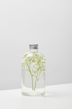 Organic cosmetic product in transparent bottle with herbs on white table isolated on grey backgroundの写真素材