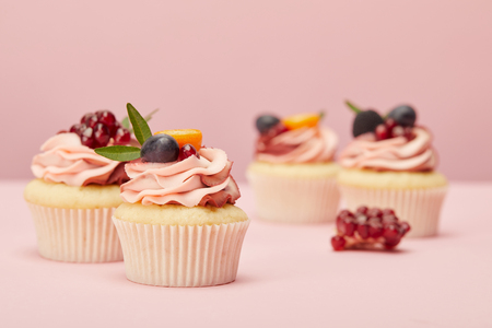 Sweet cupcakes with fruits and berries on pink surfaceの写真素材