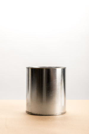 Tin of paint on beige surface on white backgroundの写真素材