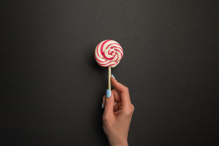 Cropped view of woman holding round tasty lollipop on black backgroundの写真素材