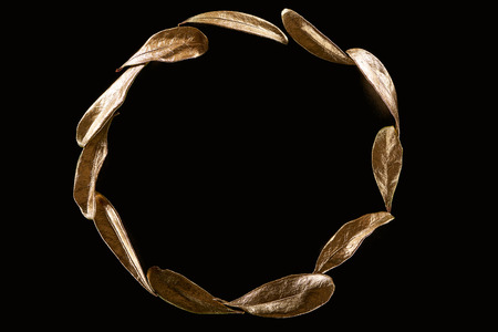 Top view of circle made of golden metal decorative leaves isolated on black with copy spaceの写真素材