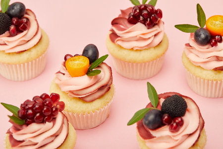 Sweet cupcakes with fruits and berries on pink surfaceの写真素材