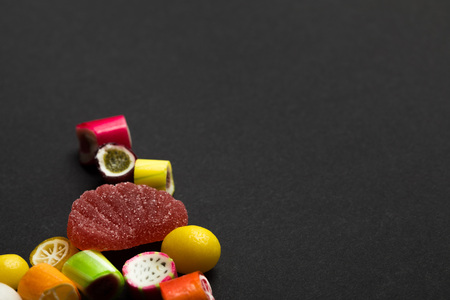 Delicious multicolored fruit caramel sweets on black background with copy spaceの写真素材