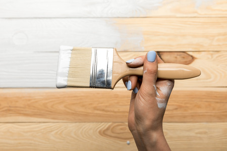 Cropped view of woman painting wooden surface in whiteの写真素材