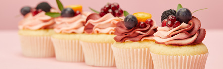 Panoramic shot of sweet cupcakes with berries and fruits on pink surfaceの写真素材