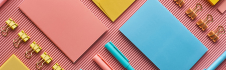 Panoramic shot of colorful stationery supplies on pink background