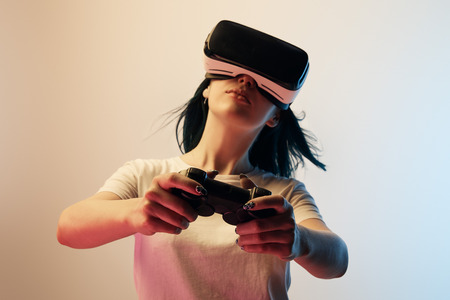 Selective focus of woman in white t-shirt wearing virtual reality headset and holding joystick on...