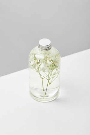 Organic beauty product in transparent bottle with herbs on white table isolated on grey backgroundの写真素材