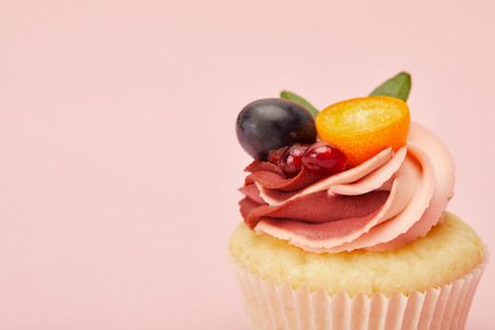 Sweet cupcake with cream and fruits isolated on pink backgroundの写真素材